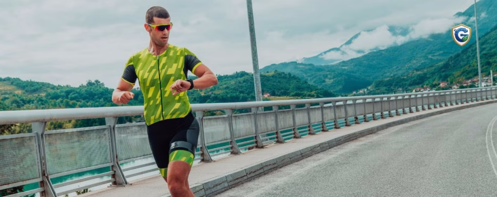 Male triathlete running on a bridge while checking his smartwatch, highlighting race preparedness, pacing, and safety during an endurance event.